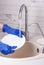 A woman in blue gloves washes a white plate under running water