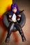 Woman with blue haircut in leather wear holding two guns sirs in the tire