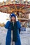 woman in a blue jacket and a green scarf and white gloves stands in winter on square in Moscow on Christmas Day