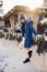 woman in a blue jacket and a green scarf and white gloves stands in winter on square in Moscow on Christmas Day