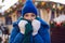 woman in a blue jacket and a green scarf and white gloves stands in winter on square in Moscow on Christmas Day