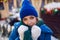 woman in a blue jacket and a green scarf and white gloves stands in winter on square in Moscow on Christmas Day