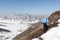 Woman in a blue jacket looking from a height to the mountains