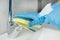 Woman with blue nitrile gloves disinfects the sink mixer after washing her hands to avoid the proliferation of viruses and