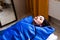 Woman in blue pressotherapy suit lying down having pressure therapy for weight loss in spa salon. Doctor help lose weight and