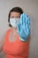 Woman with blue rubber glove make stop gesture.