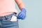 a woman in blue rubber gloves puts a protective face mask in her front jeans pocket, blue background, copy space