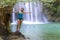 Woman in blue swimsuit stand happy at  Erawan Waterfal