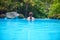 Woman in blue water. Loose hair girl in open swimming pool. Tropical jungle resort.