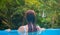 Woman in blue water. Loose hair girl in open swimming pool. Tropical jungle resort.