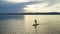 A woman on a board with a paddle loses her balance and falls into the water.