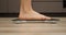 Woman on body scales. Girl barefoot checking weight, close up, side view. Female feet measuring overweight