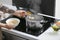 Woman boiling rice in kitchen