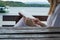 Woman with book on legs lap sitting on bench and reading near lake in nature. Relaxation and resting concept