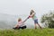 A woman in boots with her child in the form of a game mows the grass with a lawnmower in the garden