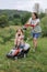 A woman in boots with her child in the form of a game mows the grass with a lawnmower in the garden