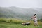 A woman in boots with her child in the form of a game mows the grass with a lawnmower in the garden