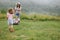 A woman in boots with her child in the form of a game mows the grass with a lawnmower in the garden