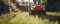 woman in boots and protective workwear cutting the grass with a riding lawnmower on a sunny day