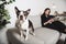 Woman with is Boston Terrier on the living room reading book