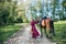 Woman with a bouquet of flowers dressed in a long burgundy dress with sleeves leads a brown hors