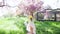 A woman with bouquet walks forward among the flowering trees