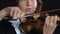 Woman bows over the strings of a violin. Black background. Close up