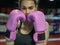 Woman boxer with pink boxing gloves looking at camera with confidence.