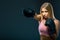 Woman in boxing gloves and sportswear strikes at workout on dark background. Copy space