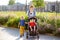 Woman with a boy and a disabled girl in a wheelchair walking in the park at summer. Child cerebral palsy. Family with disabled kid