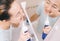 Woman with braces on her teeth brushing her teeth with by using a irrigate, before mirror, top view.