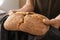 Woman breaking fresh tasty bread, closeup