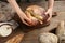 Woman breaking freshly baked bread at wooden table, closeup