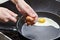Woman breaks an egg in fried eggs with knife