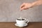 Woman brewing tea with bag in cup on table