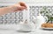 Woman brewing tea with bag in cup on table