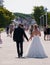 Woman in bridal gown and man in tuxedo walking on sidewalk in this tourist town after having gotten married