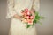 Woman bride hands holding spring flowers tulips and roses, boho wedding dress