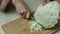 A woman on a bright kitchen table deftly finely chop white cabbage on a cutting board with a sharp kitchen knife