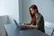 woman in bright office typing puzzled at laptop while working full time