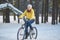 Woman in a bright yellow jacket rides a bicycle in winter in the snow