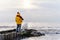 Woman in bright yellow jacket walking alone on seaside on cold winter day. Travel  Lifestyle concept