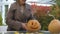 Woman brings pumpkin Jack to table in yard, preparing for autumn Halloween party