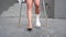Woman with broken foot walking down the street using crutches.