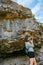 Woman with brown curly hair hiking and taking pictures with phone on the seaside by the Uugu cliff on the Muhu Island near