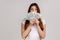 Woman with brown hair hiding face behind fan of dollars banknotes, interest-free cash withdrawal.