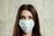 Woman with brown hair and a medical mask for protection again influenza. Shallow depth of field. Copy space for your text