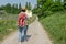 Woman with brown hair, straw hat and backpack looking at a hiking map while walking in the nature next to a wine field