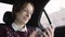 Woman with brown hair in white blouse and maroon sweater riding in car and typing message with a smile