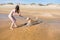 Woman bruenette in bikini playing with his fawn dog Labrador on the seashore, takes on the camera